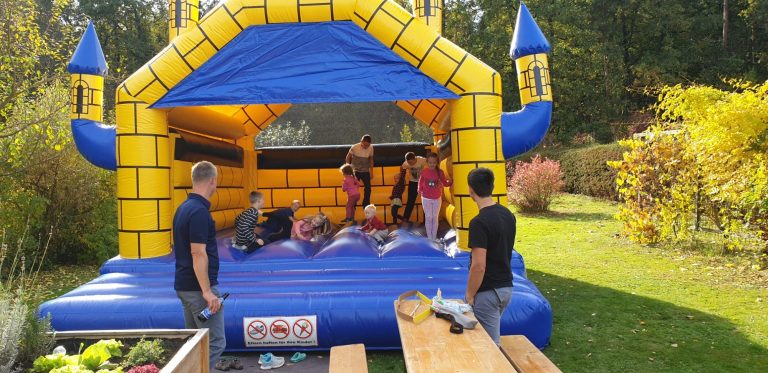Farbenfroher Hüpfburg mit Kindern, die spielen, und Erwachsenen in der Nähe.