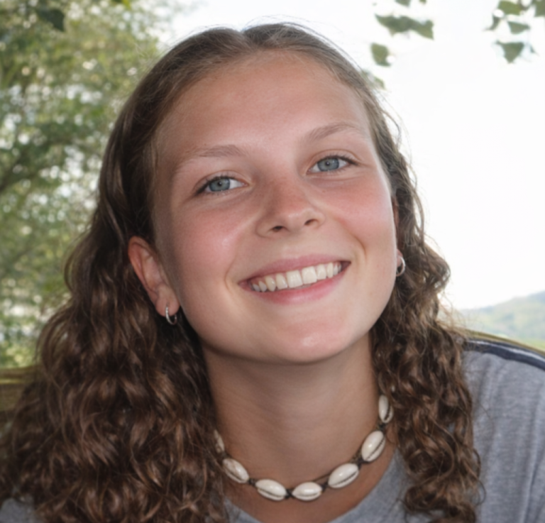 Lisa Janson Lächelnde junge Frau mit lockigem Haar und Muschelkette, im Freien.