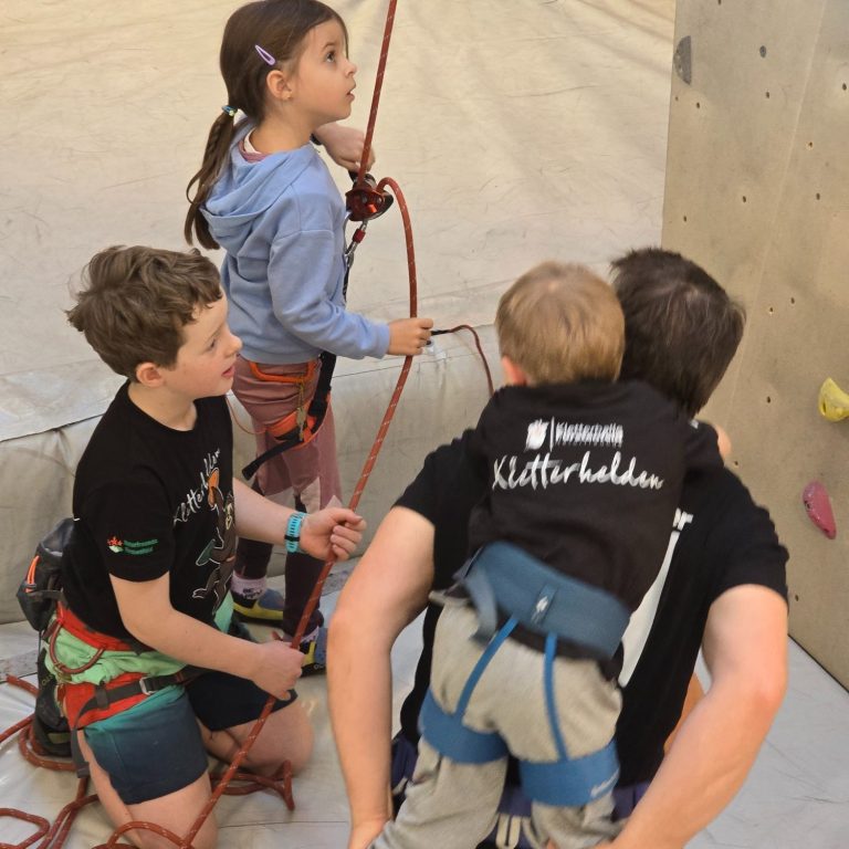 Kletterer beim Wettkampf in einer Kletterhalle mit Felsenwand.